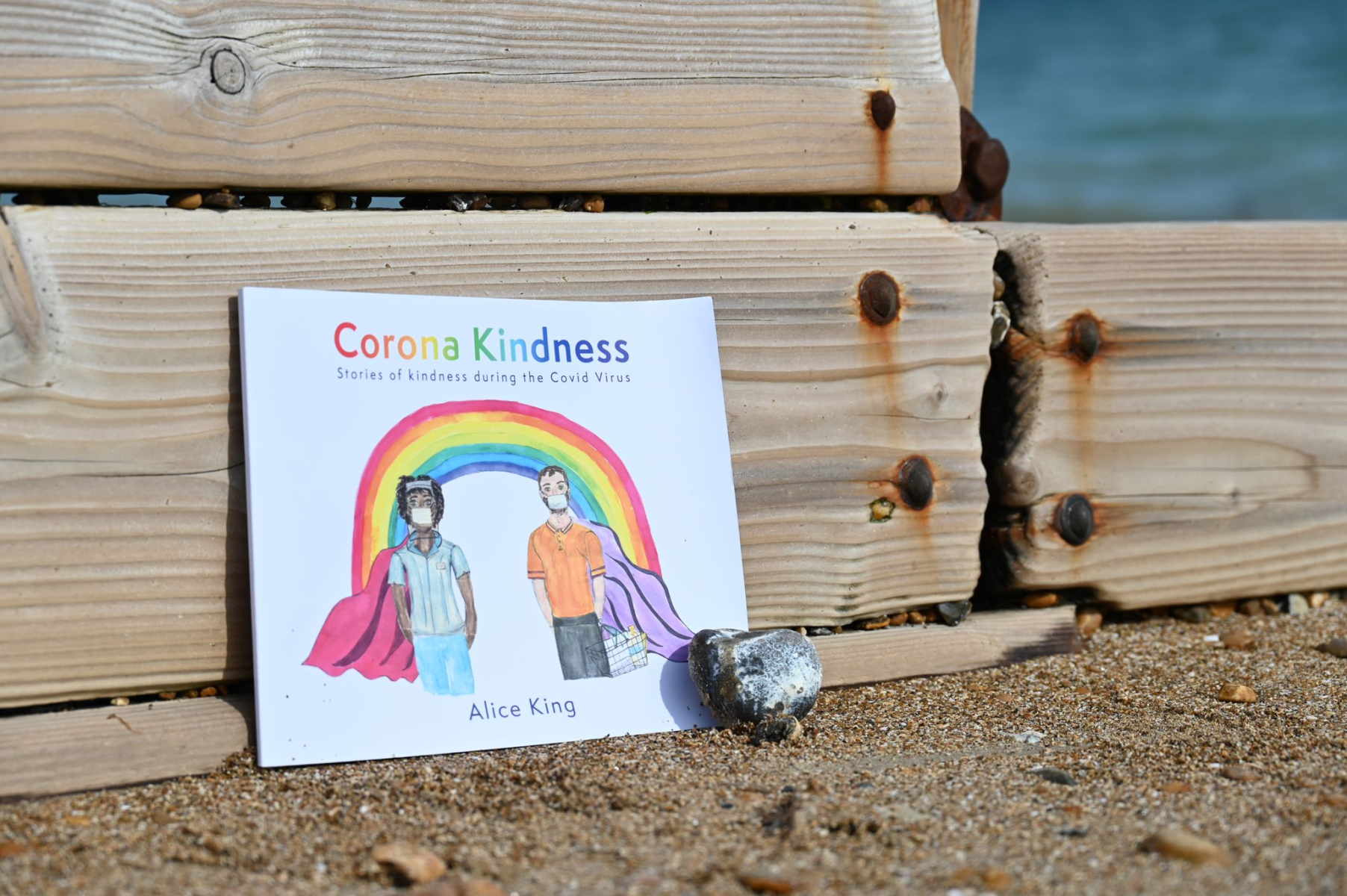 Corona Kindness book next to a beach groyne