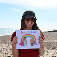 The author with her Corona Kindness book on a beach