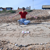 Corona Kindness written in sand on a beach