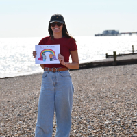 The author with her Corona Kindness book on a beach